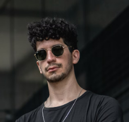 Man with curly hair wearing sunglasses.